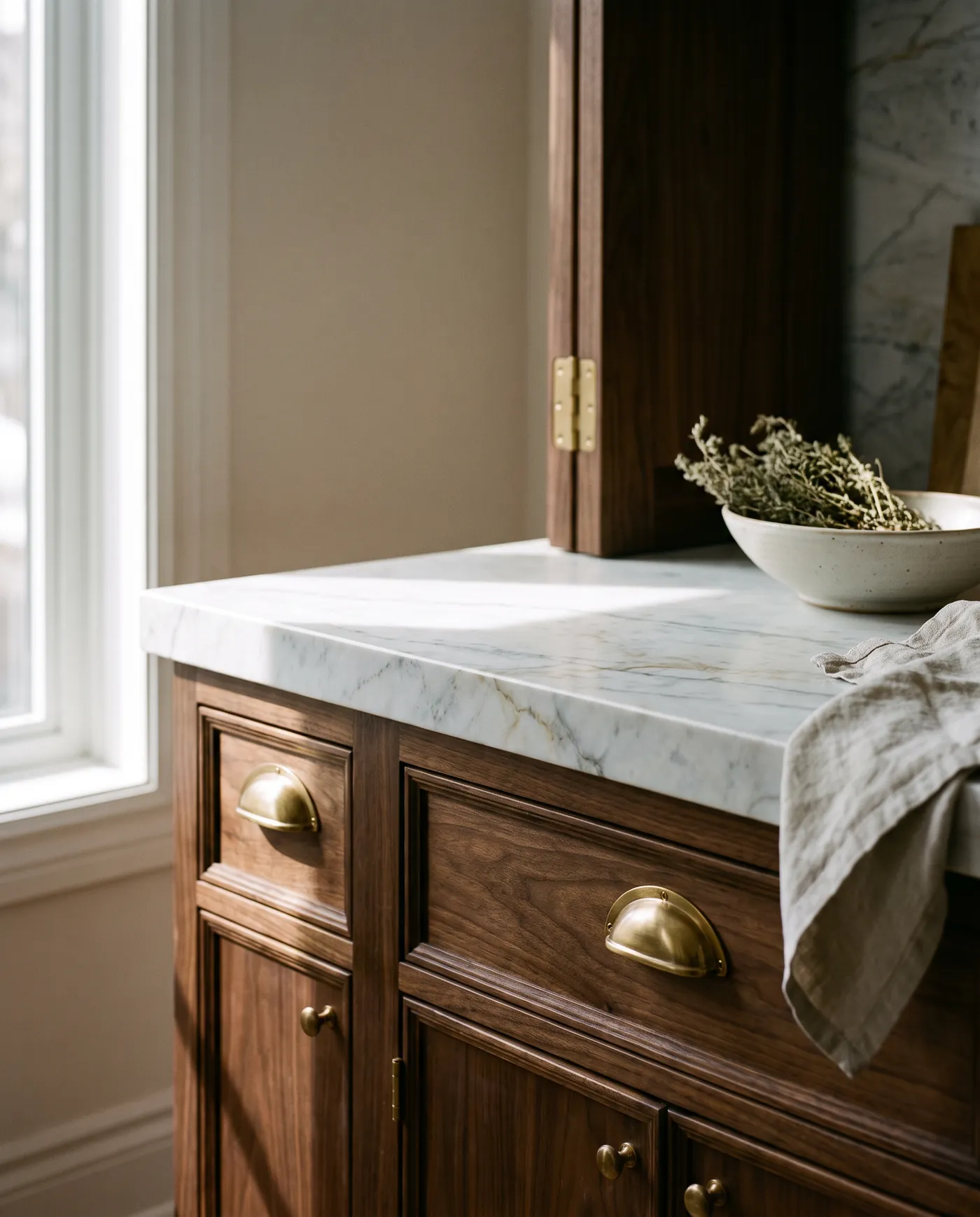 Walnut cabinetry meeting a honed marble countertop with brass hardware